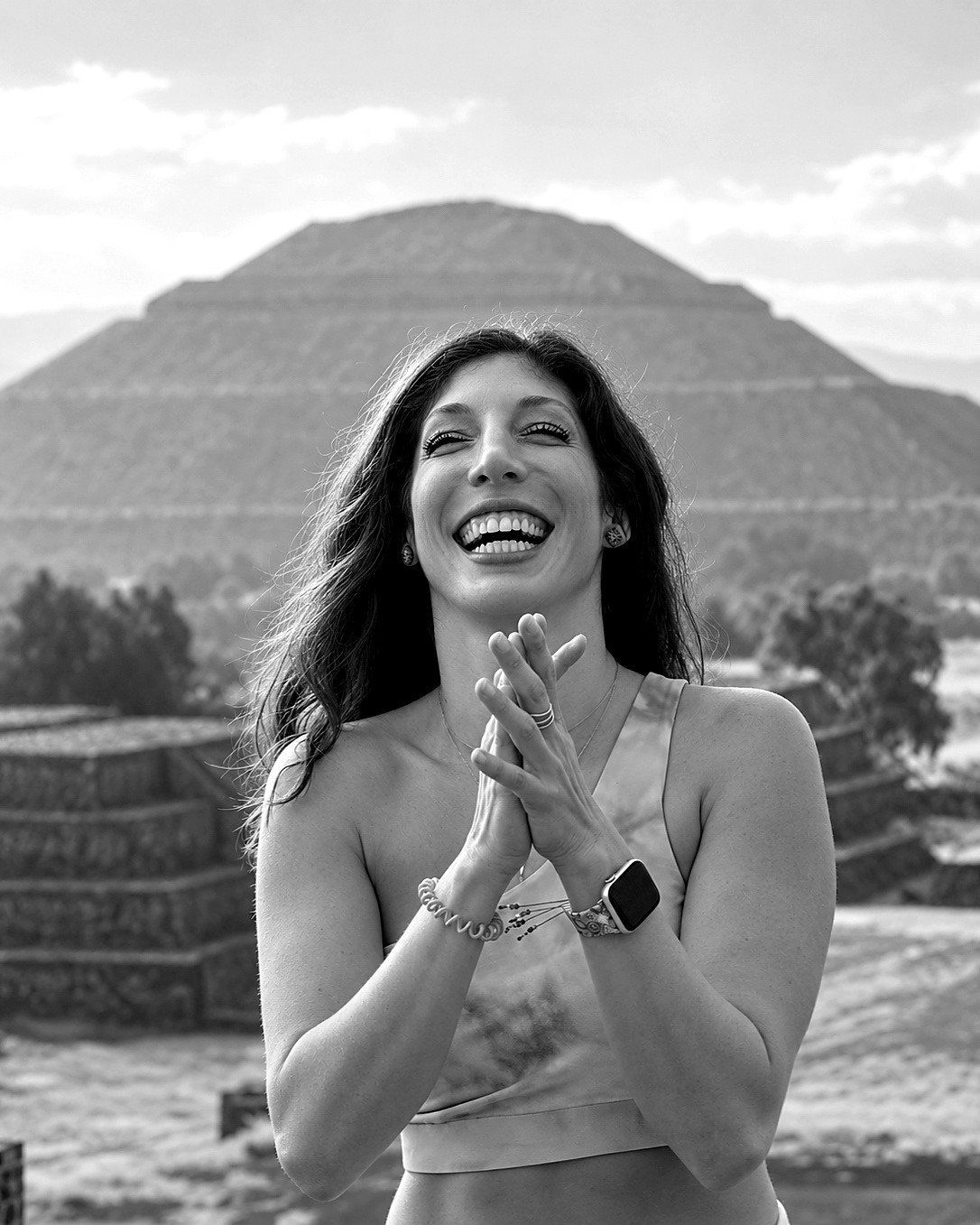 Sara Maya laughing with her hands clasped in front of an ancient pyramid
